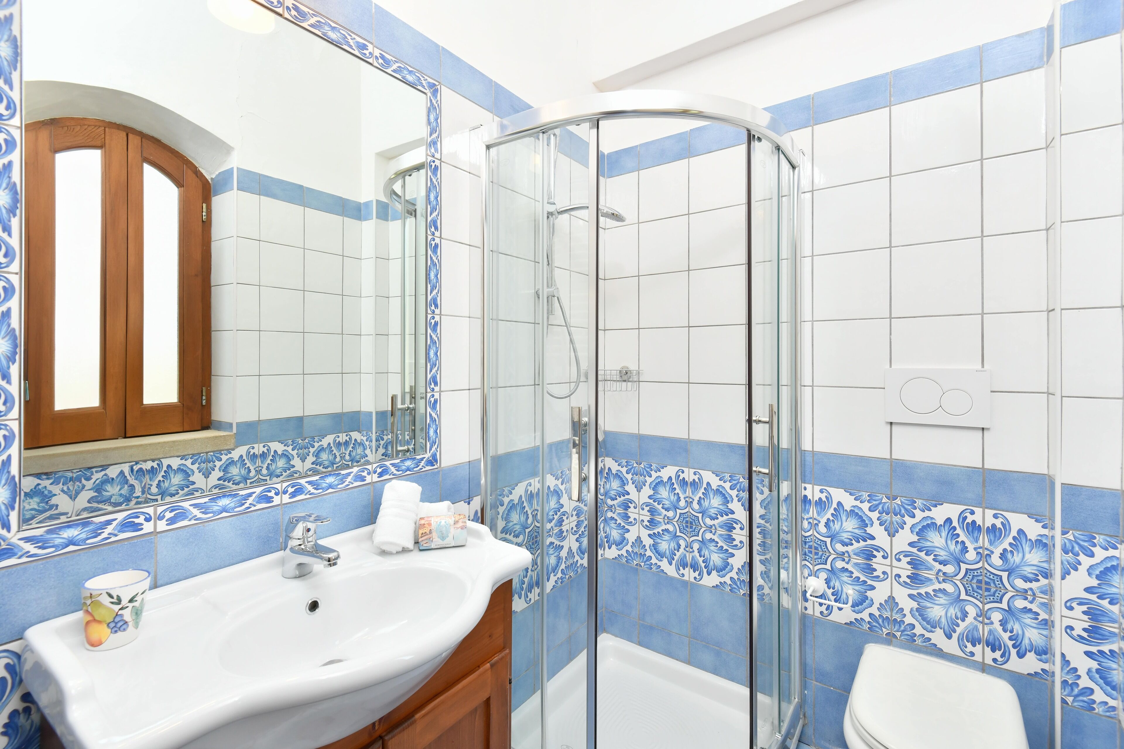 A bathroom with a glass shower enclosure, a sink with a mirror, and a toilet.