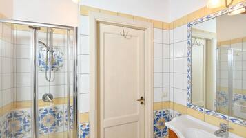 A bathroom with a shower, a sink, and a mirror.