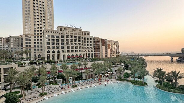 A high-rise hotel with a swimming pool and palm trees. - Stylish 1 BD Near the Lagoon in Creek Harbour (Dubai)