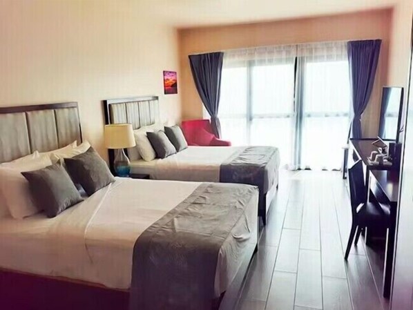 A hotel room with two beds, a desk, and a chair.
