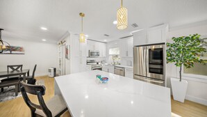 A modern kitchen with white cabinetry, stainless steel appliances, and a marble island. - Ultimate Vacation Spot: Pool, Mini Golf & Hammock! (Tampa)