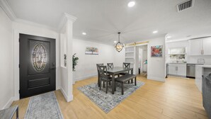 A dining area with a table and chairs, a chandelier, and a kitchen in the background. - Ultimate Vacation Spot: Pool, Mini Golf & Hammock! (Tampa)