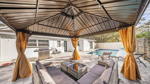 An outdoor patio with a covered seating area, a pool, and a barbecue grill. - Ultimate Vacation Spot: Pool, Mini Golf & Hammock! (Tampa)