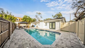 A backyard with a swimming pool, a wooden deck, and a fenced area. - Ultimate Vacation Spot: Pool, Mini Golf & Hammock! (Tampa)