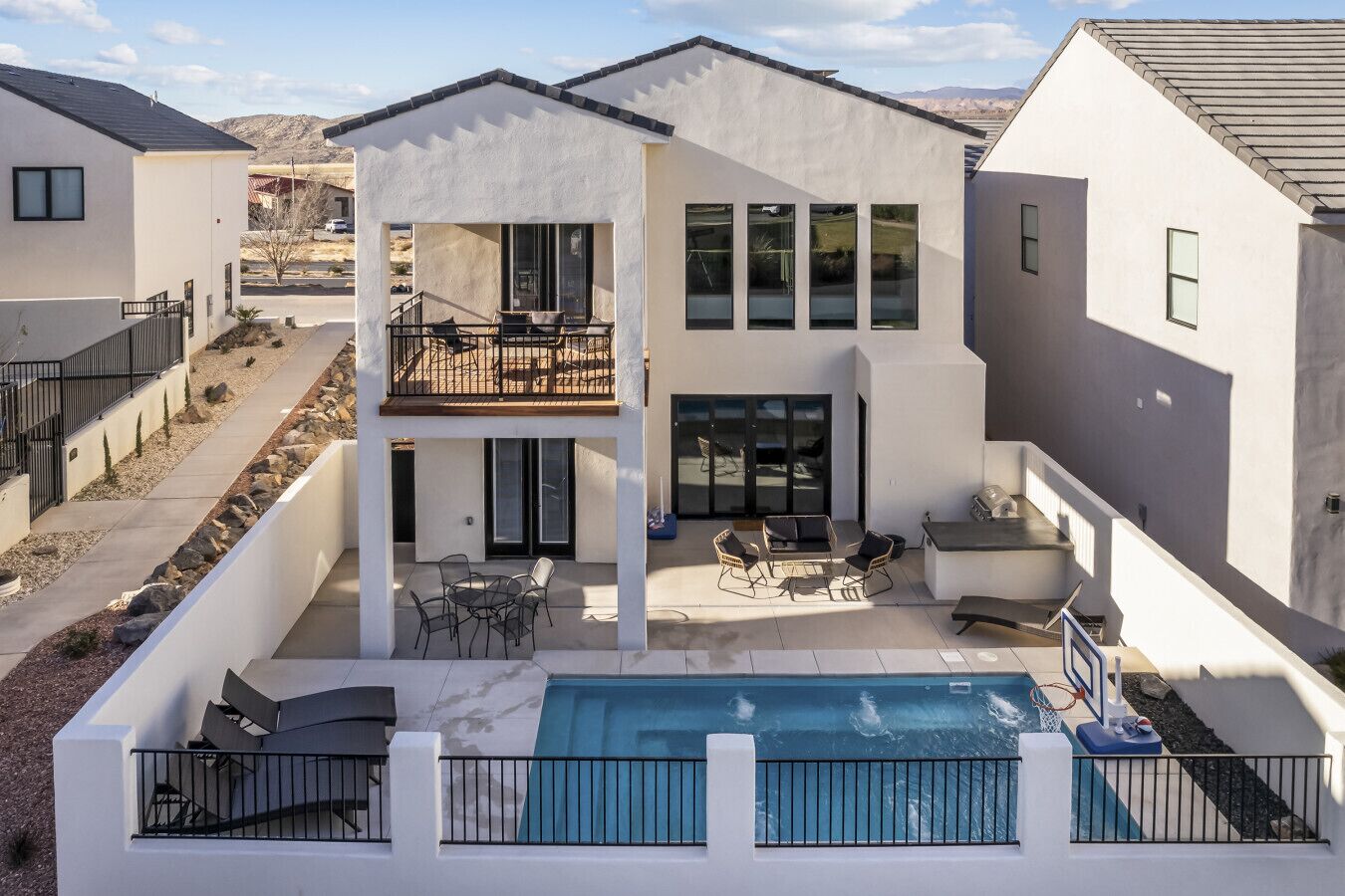 A modern two-story house with a pool, outdoor seating, and a balcony.