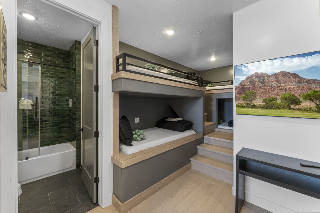 Una habitación compacta con una cama litera, cabina de ducha de vidrio y vistas a un paisaje montañoso.