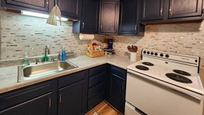 A kitchen with dark cabinets, a white stove, and a tiled backsplash.
