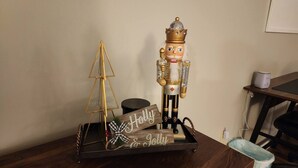 A wooden tray with a nutcracker, a small golden pyramid, and a sign that reads "Holly & Jolly".