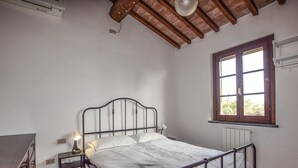 A bedroom with a metal bed frame, a bedside table with a lamp, a window with a view, and a radiator. - Cozy home in Fauglia with WiFi (Fauglia)