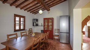 A dining area with a wooden table and chairs, a cabinet with glass doors, a refrigerator, and a window with a view. - Cozy home in Fauglia with WiFi (Fauglia)