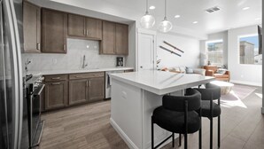 A modern kitchen with wooden cabinets, a white island, and pendant lighting. - Luxury 3 bed / 3 bath townhome in Park City, Sauna, 10 min to world-class skiing (Park City)