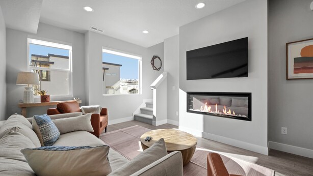 A modern living room with a fireplace, a large TV mounted on the wall, and a staircase leading to an upper level. - Luxury 3 bed / 3 bath townhome in Park City, Sauna, 10 min to world-class skiing (Park City)