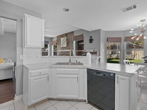 Functional kitchen setup, complete with a dual sink, a black dishwasher, and a handy breakfast bar.