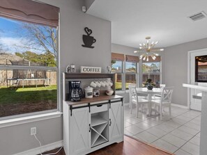 A delightful coffee bar station with sliding barn doors overlooks the bright dining area, featuring a white table setup.