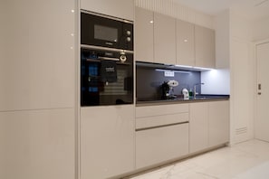 A modern kitchen with built-in appliances, a countertop, and a door with a towel hanging.