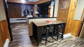 Una habitación acogedora con suelo de madera, una mesa de comedor con sillas, un armario y un letrero en la pared.