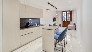 Una cocina moderna con una isla central, taburetes de bar y una zona de comedor con sofá.