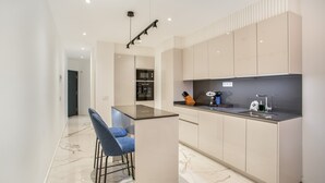 Una cocina moderna con encimera de mármol, horno empotrado y una barra con taburetes.