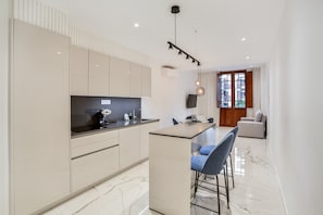 A modern kitchen with a central island, bar stools, and a dining area with a sofa.