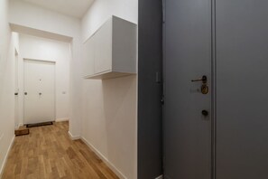 A hallway with wooden flooring, white walls, and a grey door with a keyhole. - Vaccinari al Ghetto - FromHometoRome (Roma)