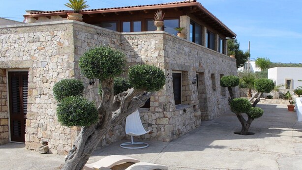 A stone building with a tiled roof, a tree with a white chair in front, and a small patio area. - Villa 'La  -  Liscedde' with Sea View, Wi-Fi and Air Conditioning (Castrignano del capo)