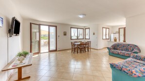 A spacious living area with a dining table, a sofa, and a television mounted on the wall. - Villa 'La  -  Liscedde' with Sea View, Wi-Fi and Air Conditioning (Castrignano del capo)
