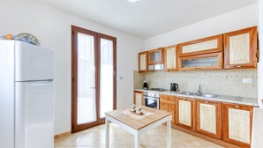 A kitchen with wooden cabinets, a white refrigerator, a stove, and a sink. - Villa 'La  -  Liscedde' with Sea View, Wi-Fi and Air Conditioning (Castrignano del capo)