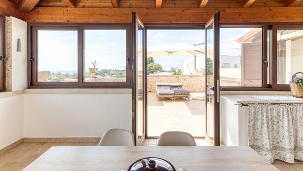 A room with a wooden ceiling, large sliding glass doors, a table, and chairs. - Villa 'L'attico' with Sea View, Private Terrace and Wi-Fi (Castrignano del capo)