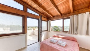 A bedroom with a wooden ceiling, large windows, a bed with pink bedding, and a view of the outdoors. - Villa 'L'attico' with Sea View, Private Terrace and Wi-Fi (Castrignano del capo)