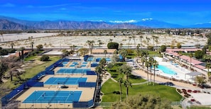 An aerial view of a resort with multiple tennis courts, a swimming pool, and a mountainous backdrop. - Fairway Gem: Pool+Spa, BBQ, Putting Green, EV Charger! (Indio)