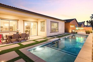 A modern residential property with a swimming pool, outdoor seating, and a well-maintained lawn.