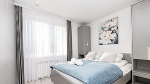 Une chambre à coucher moderne avec un lit, une armoire grise et un tableau accroché au mur.