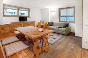 A cozy living area with a wooden dining table, cushioned benches, a sofa, and a television. - Chalet 'Pieri - Appartamento Temelin' with Mountain View and Wi-Fi (Bormio)