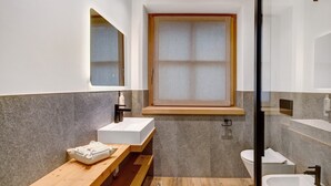 Une salle de bain moderne avec un meuble-lavabo en bois, une grande fenêtre et une cabine de douche en verre.
