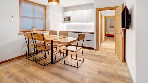 Une cuisine moderne avec des meubles blancs, une table à manger en bois et des chaises.