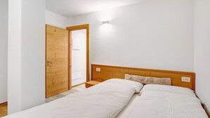 Une chambre avec deux lits simples, une porte en bois et une petite table de chevet.
