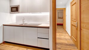 Une cuisine moderne avec des armoires blanches, un four à micro-ondes encastré et un plancher en bois.
