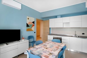 A compact living space with a dining area, a kitchen, and a TV.