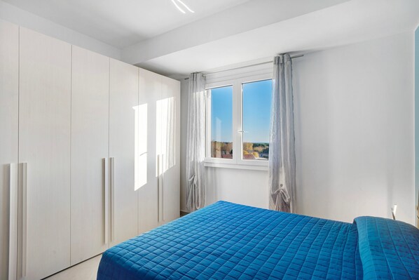 A bedroom with a bed, a window with curtains, and a wardrobe.