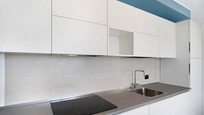 A modern kitchen with white cabinets, a stainless steel sink, and a black countertop. - Apartment 'Iris' with Sea View, Private Terrace and Air Conditioning (Albenga)