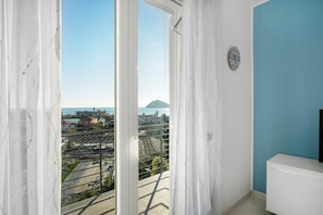 A room with a view of a cityscape, a white wall, and a clock.
