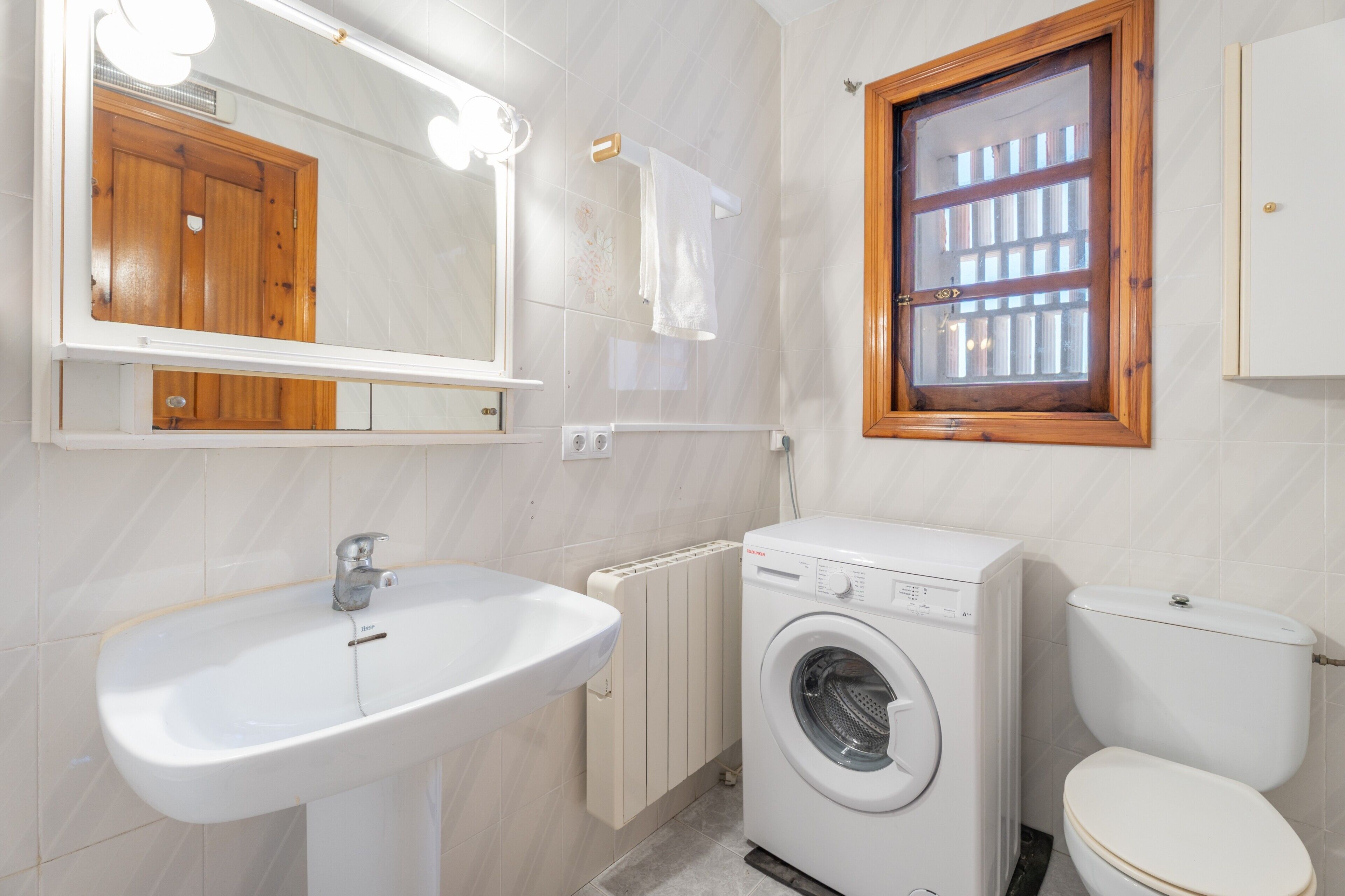 Une salle de bain équipée d’un lavabo, d’une machine à laver et de toilettes.