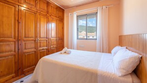 Ein Schlafzimmer mit einem Bett, einem Holzschrank und einem Fenster mit Vorhängen.
