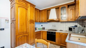 A kitchen with wooden cabinets, a stove, a microwave, and a sink. - Apartment 'Daniela' with Mountain View, Balcony and Wi-Fi (Druogno)