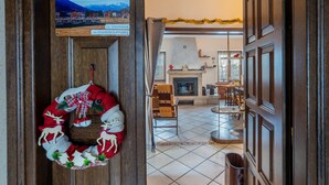 A wooden door with a Christmas wreath, a fireplace, and a dining area with chairs and a table. - Apartment 'Daniela' with Mountain View, Balcony and Wi-Fi (Druogno)
