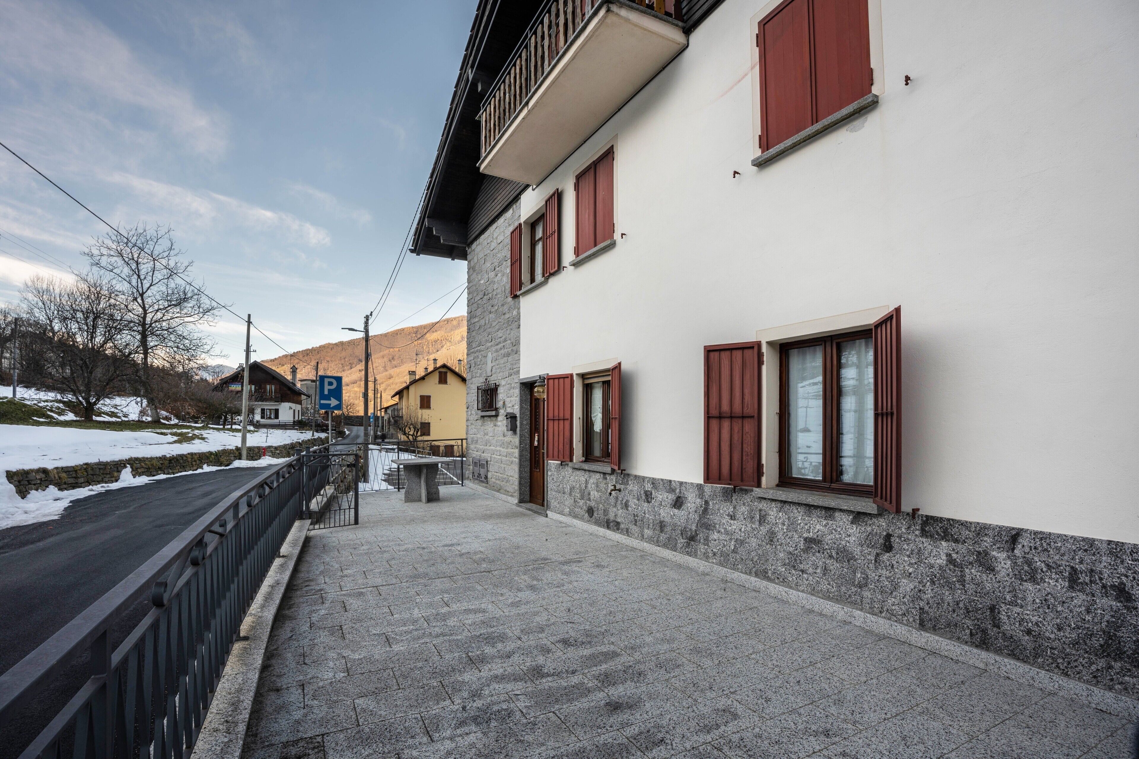 Ein Gebäude mit einer Steinaußenwand, roten Fensterläden und einem gepflasterten Weg.