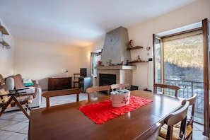 Un comedor con mesa de madera, sillas, un mantel individual rojo y un jarrón decorativo.