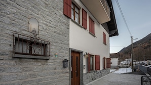 A stone building with a wooden door, red shutters, and a metal balcony. - Apartment 'Daniela' with Mountain View, Balcony and Wi-Fi (Druogno)