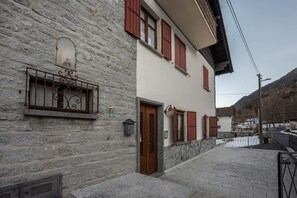 A stone building with a wooden door, red shutters, and a metal balcony. - Apartment 'Daniela' with Mountain View, Balcony and Wi-Fi (Druogno)