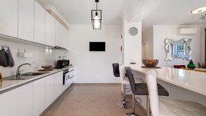 Eine moderne Küche mit weißen Schränken, einem eingebauten Ofen, einer Spüle und einer Bar mit Hockern.